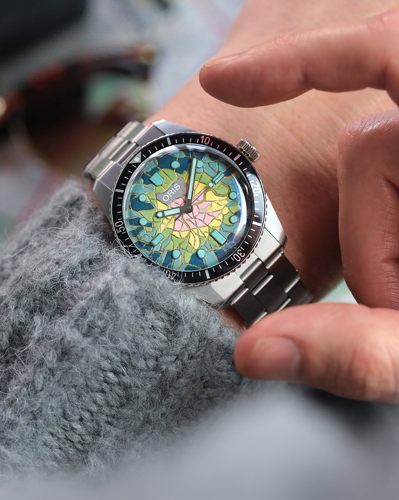 Close-up of a hand wearing a colorful wristwatch with a detailed face.